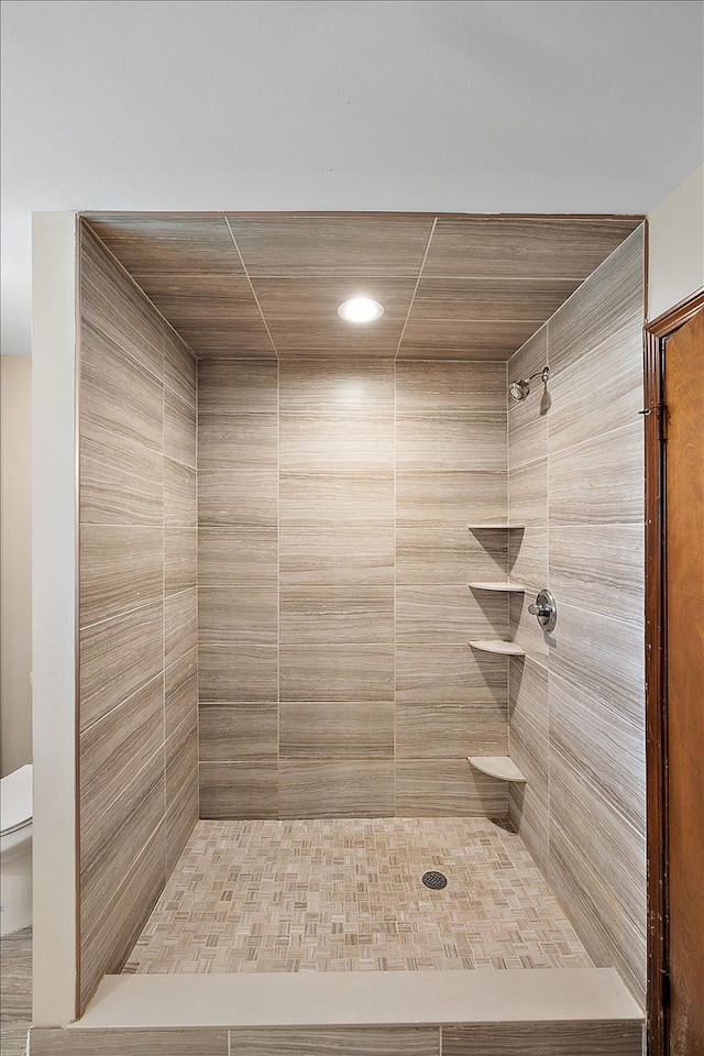 bathroom featuring tiled shower and toilet