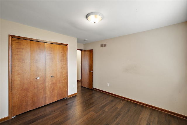 unfurnished bedroom with a closet and dark wood-type flooring