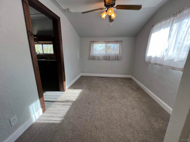 empty room with vaulted ceiling, ceiling fan, and a healthy amount of sunlight