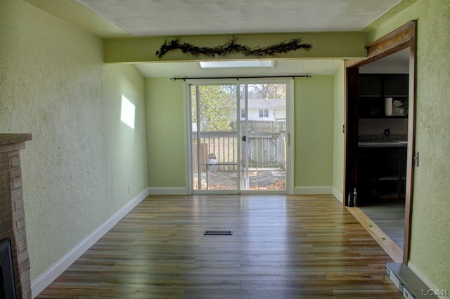 interior space with wood-type flooring and a brick fireplace