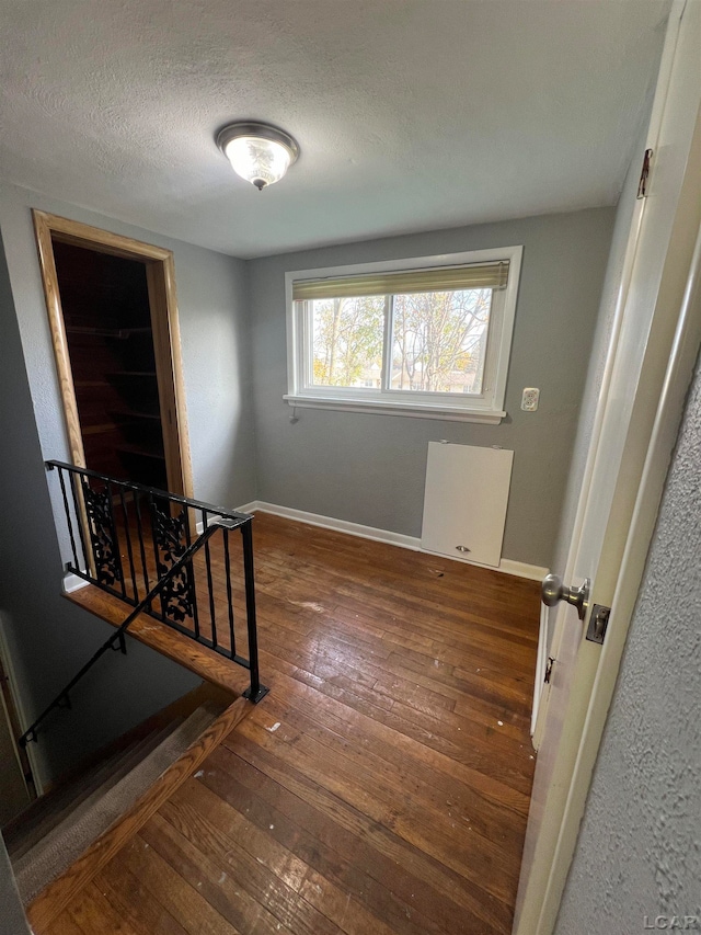 unfurnished room with dark wood-type flooring and a textured ceiling