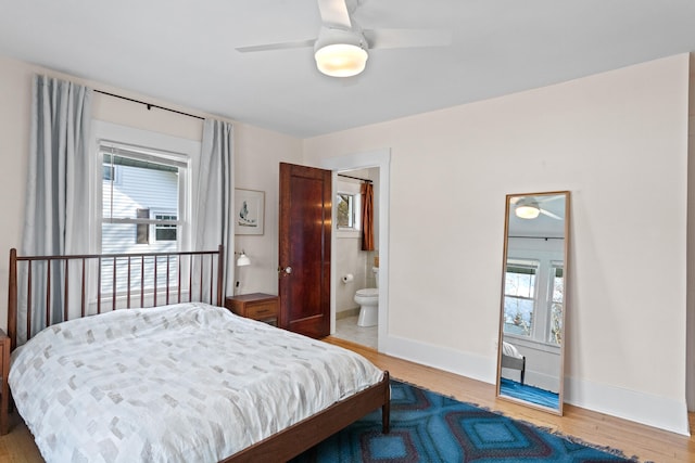 bedroom featuring ensuite bath, ceiling fan, wood-type flooring, and multiple windows