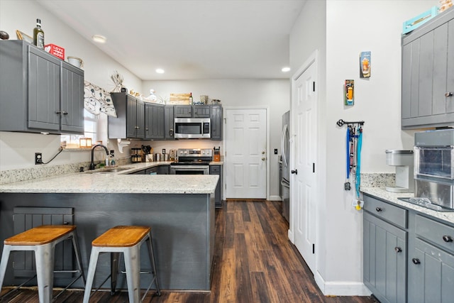 kitchen featuring gray cabinetry, a breakfast bar, sink, dark hardwood / wood-style flooring, and kitchen peninsula