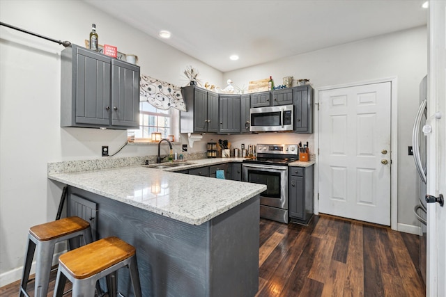 kitchen featuring kitchen peninsula, gray cabinetry, stainless steel appliances, sink, and dark hardwood / wood-style floors