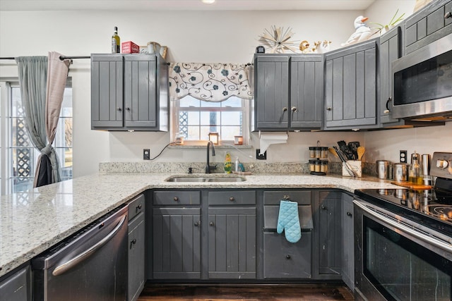 kitchen with light stone countertops, appliances with stainless steel finishes, gray cabinets, and sink