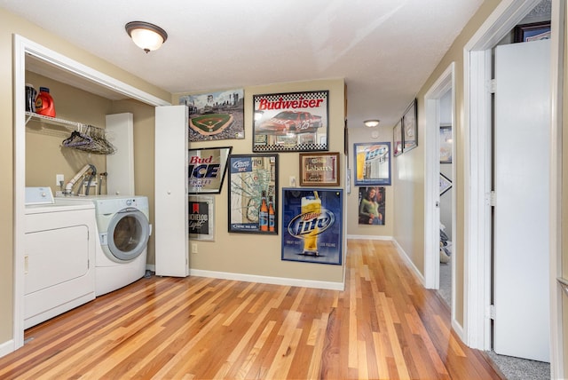 clothes washing area with hardwood / wood-style flooring and washing machine and dryer