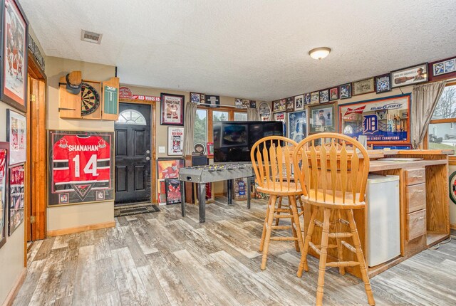 5085 W Redstone Rd, Michigan, MI 48880 - dining room featuring a textured ceiling, wood finished floors, a bar, and baseboards