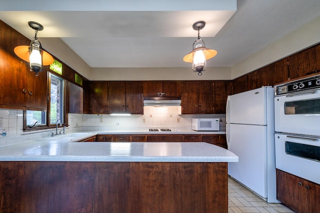 kitchen featuring kitchen peninsula, decorative light fixtures, and white appliances