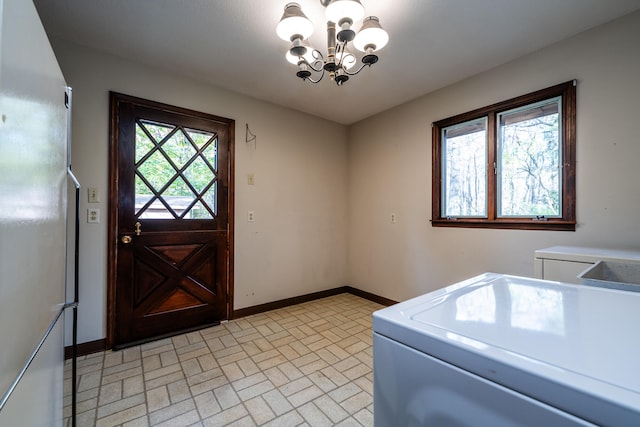 clothes washing area featuring a wealth of natural light, washer / clothes dryer, and an inviting chandelier