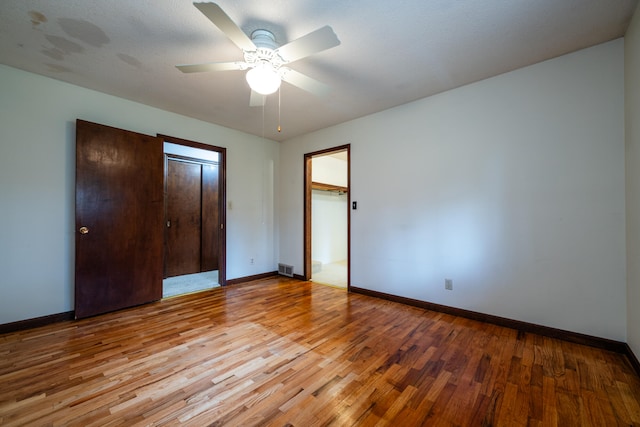 unfurnished bedroom with a textured ceiling, light wood-type flooring, a closet, and ceiling fan