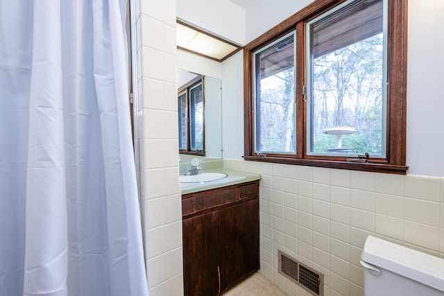 bathroom featuring vanity, toilet, and tile walls