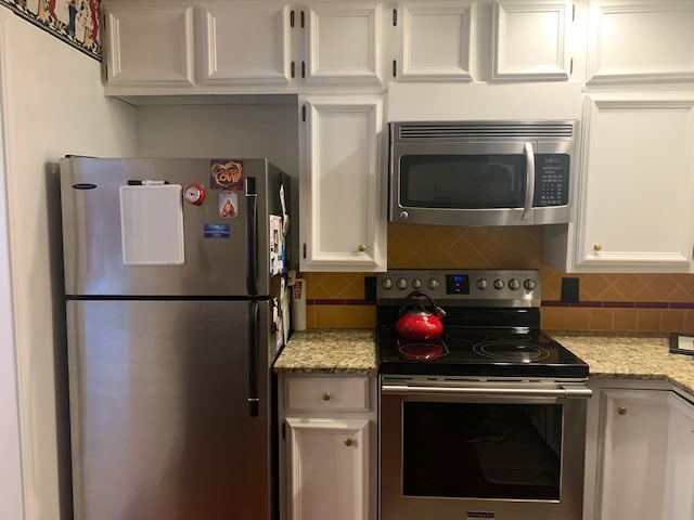 kitchen featuring backsplash, white cabinetry, light stone counters, and appliances with stainless steel finishes