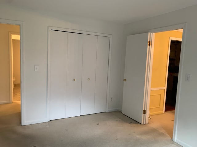 unfurnished bedroom with light carpet and a closet