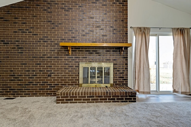 unfurnished living room with a brick fireplace, brick wall, a wealth of natural light, and vaulted ceiling