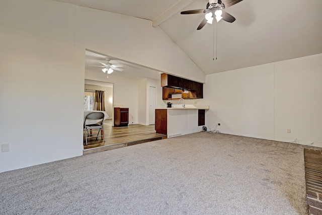 unfurnished living room featuring beam ceiling, carpet flooring, ceiling fan, sink, and high vaulted ceiling