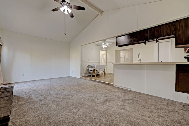 unfurnished living room with beam ceiling, ceiling fan, carpet flooring, and high vaulted ceiling