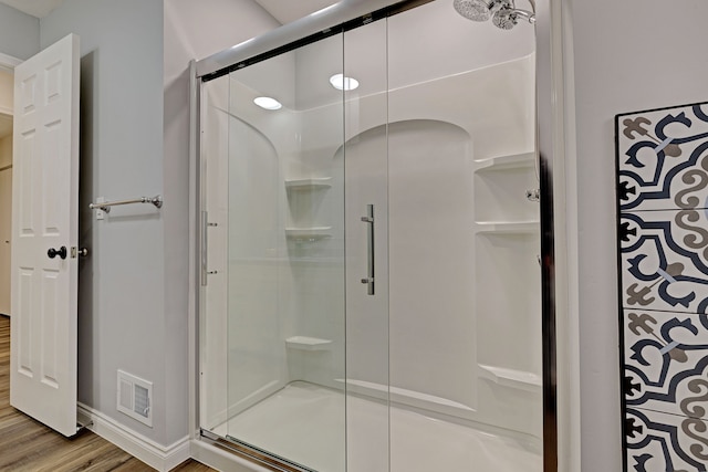 bathroom with a shower with door and hardwood / wood-style flooring