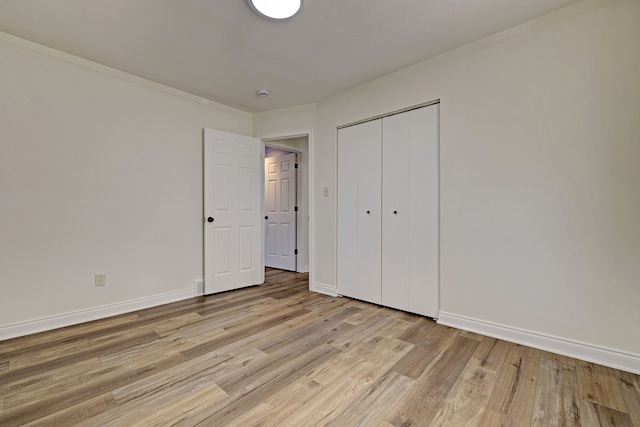 unfurnished bedroom with light wood-type flooring, a closet, and crown molding