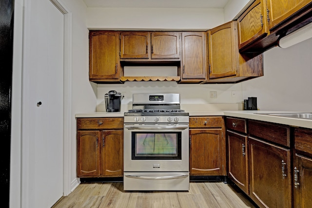 kitchen with light hardwood / wood-style flooring, exhaust hood, and gas range