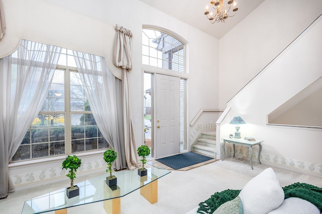 carpeted foyer entrance featuring high vaulted ceiling and a notable chandelier