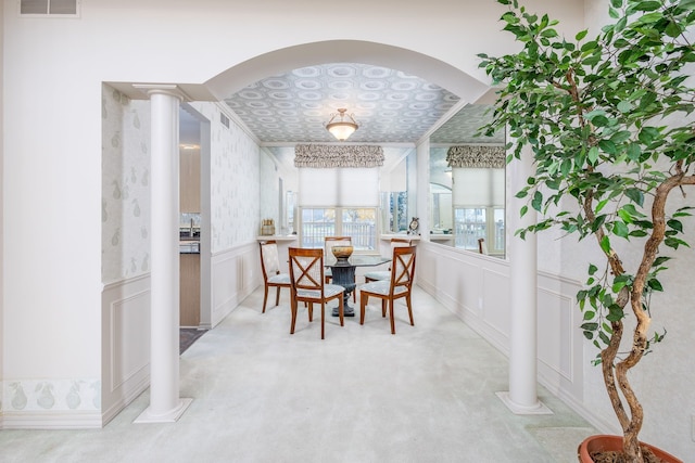 carpeted dining space featuring decorative columns