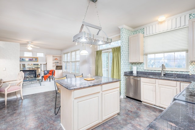 kitchen with dishwasher, sink, hanging light fixtures, a fireplace, and a kitchen island