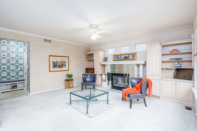 living room with ceiling fan, crown molding, light carpet, and a tiled fireplace