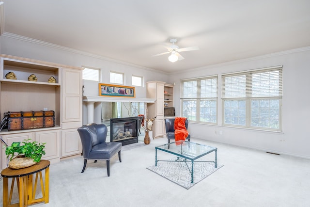 living room with ceiling fan, a fireplace, light colored carpet, and ornamental molding