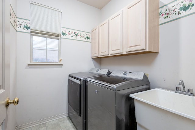 clothes washing area with washer and clothes dryer, cabinets, and sink