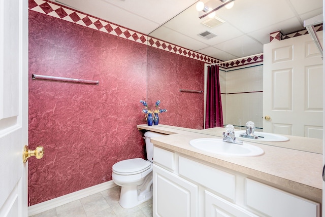 bathroom featuring vanity, a drop ceiling, tile patterned flooring, and toilet