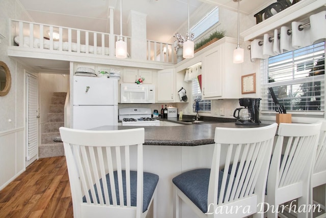 kitchen featuring a kitchen breakfast bar, white appliances, dark wood-type flooring, sink, and white cabinetry