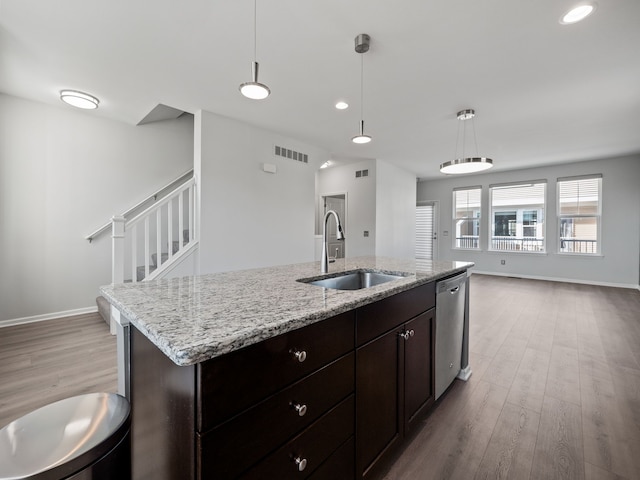 kitchen featuring pendant lighting, sink, stainless steel dishwasher, and light hardwood / wood-style floors