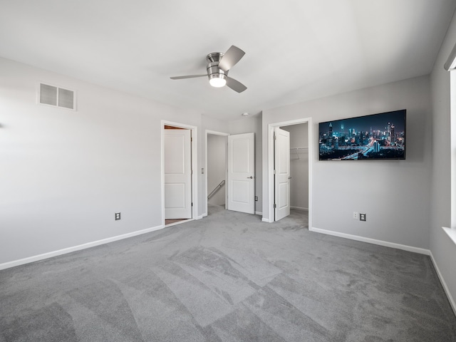 unfurnished bedroom with carpet flooring, ceiling fan, a walk in closet, and a closet