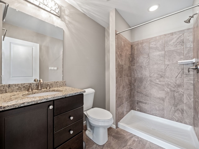 bathroom with a tile shower, vanity, toilet, and tile patterned floors