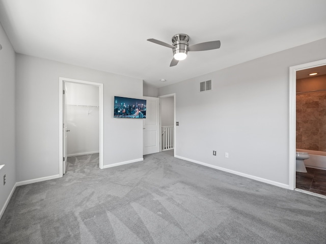 unfurnished bedroom featuring a walk in closet, ceiling fan, connected bathroom, light colored carpet, and a closet