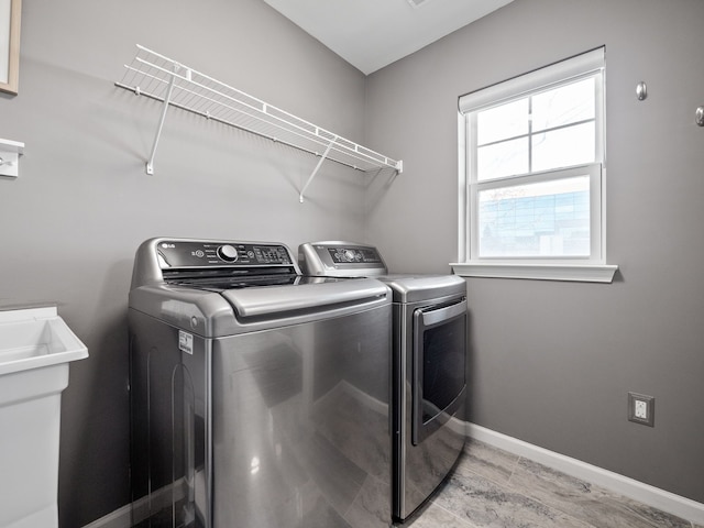 clothes washing area with light wood-type flooring and washer and clothes dryer