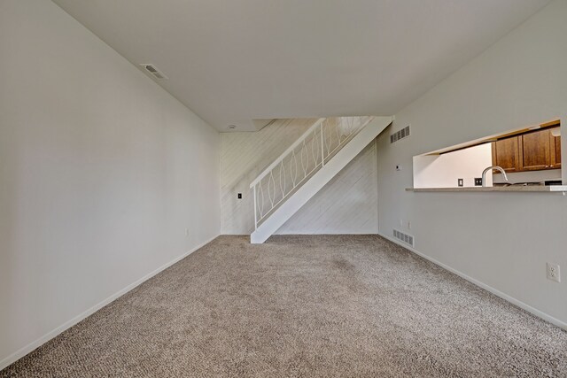 2765 Fox Hollow Ct, Lake Orion, MI 48360 - unfurnished living room featuring carpet flooring, stairs, baseboards, and a sink