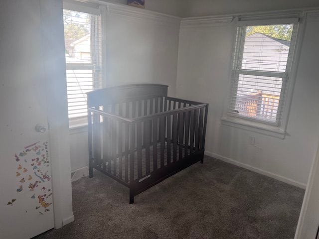 bedroom featuring dark colored carpet and a crib