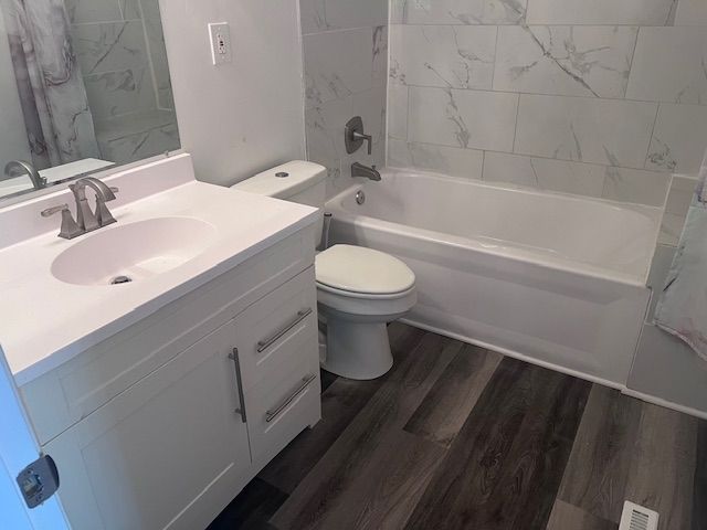 full bathroom featuring shower / bath combo, vanity, hardwood / wood-style flooring, and toilet