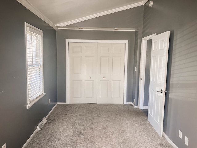 unfurnished bedroom featuring carpet flooring, a closet, lofted ceiling, and ornamental molding