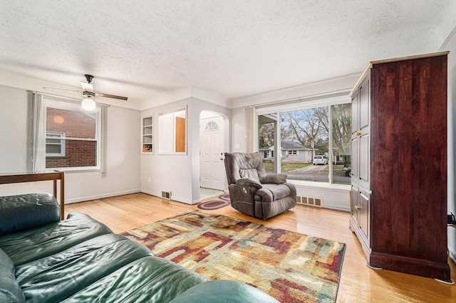 living room featuring ceiling fan, a textured ceiling, and light hardwood / wood-style flooring