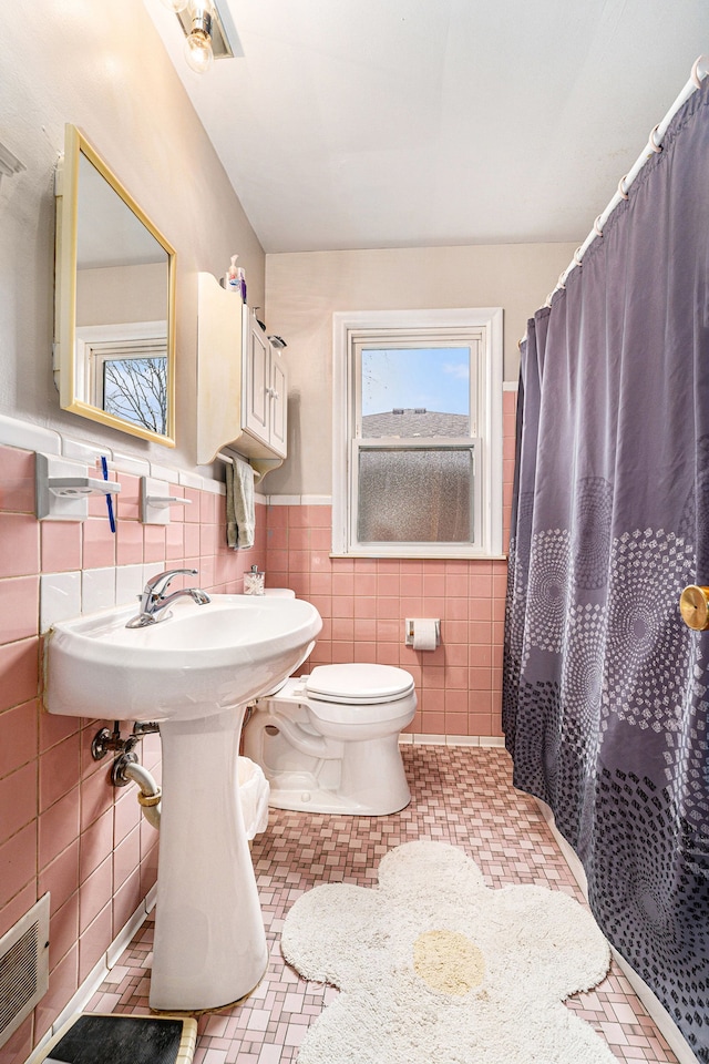 bathroom with tile patterned flooring, curtained shower, toilet, and tile walls