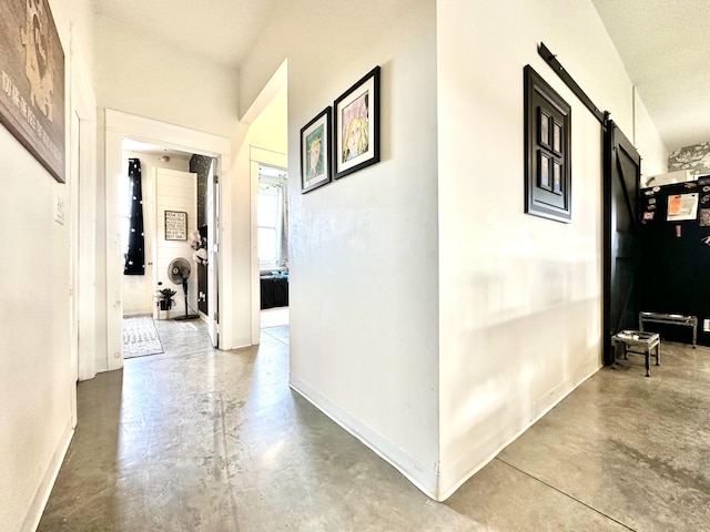 hall featuring a textured ceiling, concrete floors, and a barn door