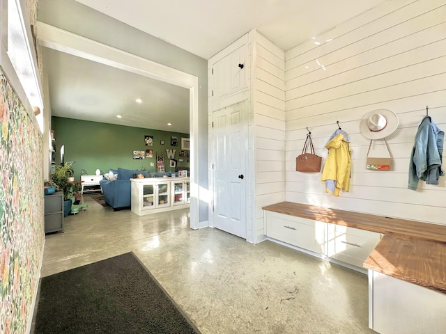 mudroom with concrete flooring and wooden walls