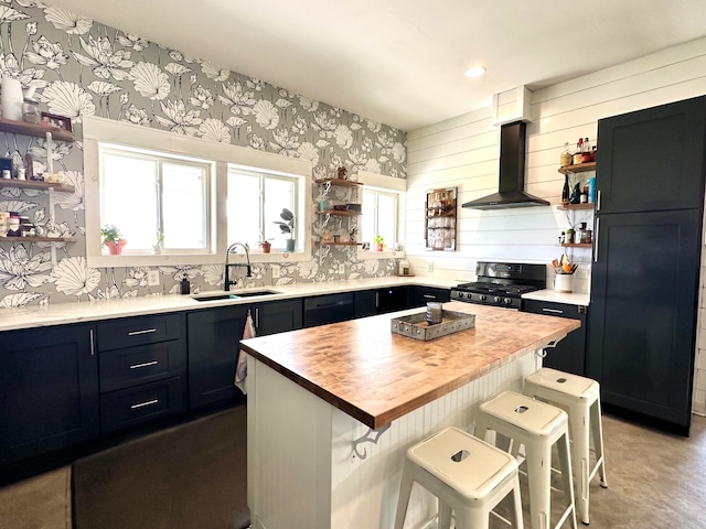 kitchen with a center island, exhaust hood, a kitchen breakfast bar, sink, and black gas range oven