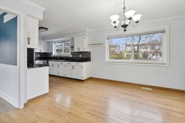 kitchen with decorative backsplash, crown molding, decorative light fixtures, white cabinets, and light hardwood / wood-style floors