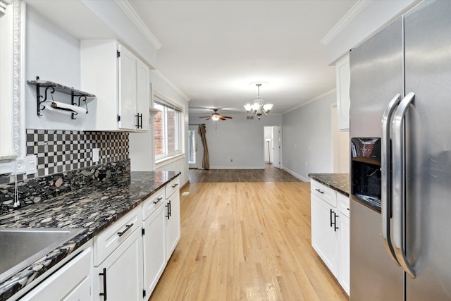 kitchen with dark stone counters, ceiling fan with notable chandelier, light hardwood / wood-style flooring, white cabinets, and stainless steel fridge with ice dispenser