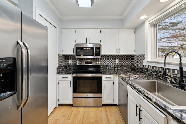 kitchen featuring ornamental molding, stainless steel appliances, sink, light hardwood / wood-style flooring, and white cabinets