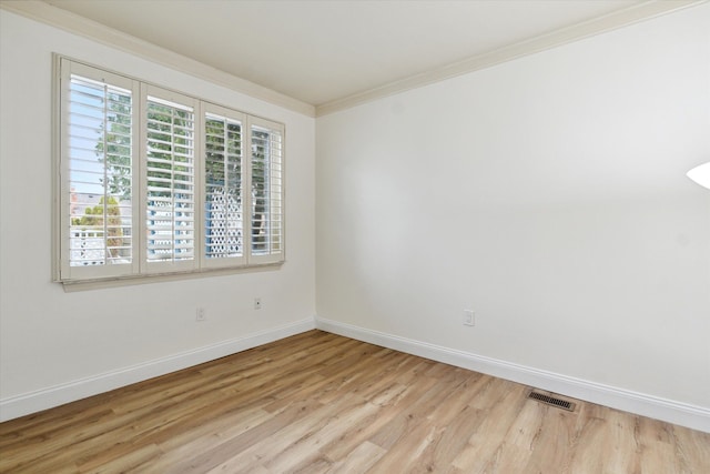 empty room with crown molding and light hardwood / wood-style floors