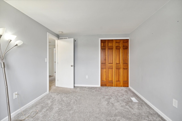 unfurnished bedroom featuring light carpet and a closet